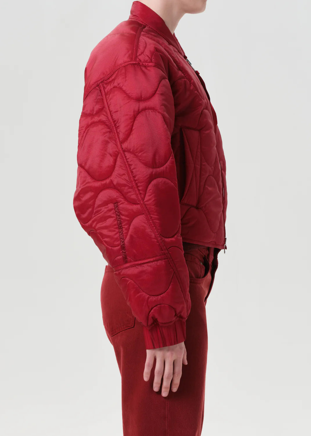 Red quilted jacket worn by a person on a white background