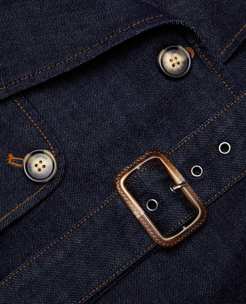 Close-up of a dark blue denim jacket with buttons and a buckle.