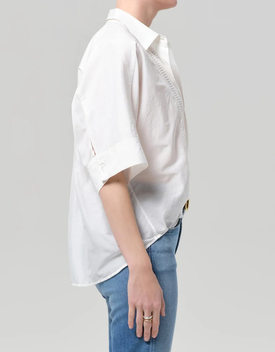 Side view of the white Claire shirt showing the wide short sleeve and lace inset at the front
