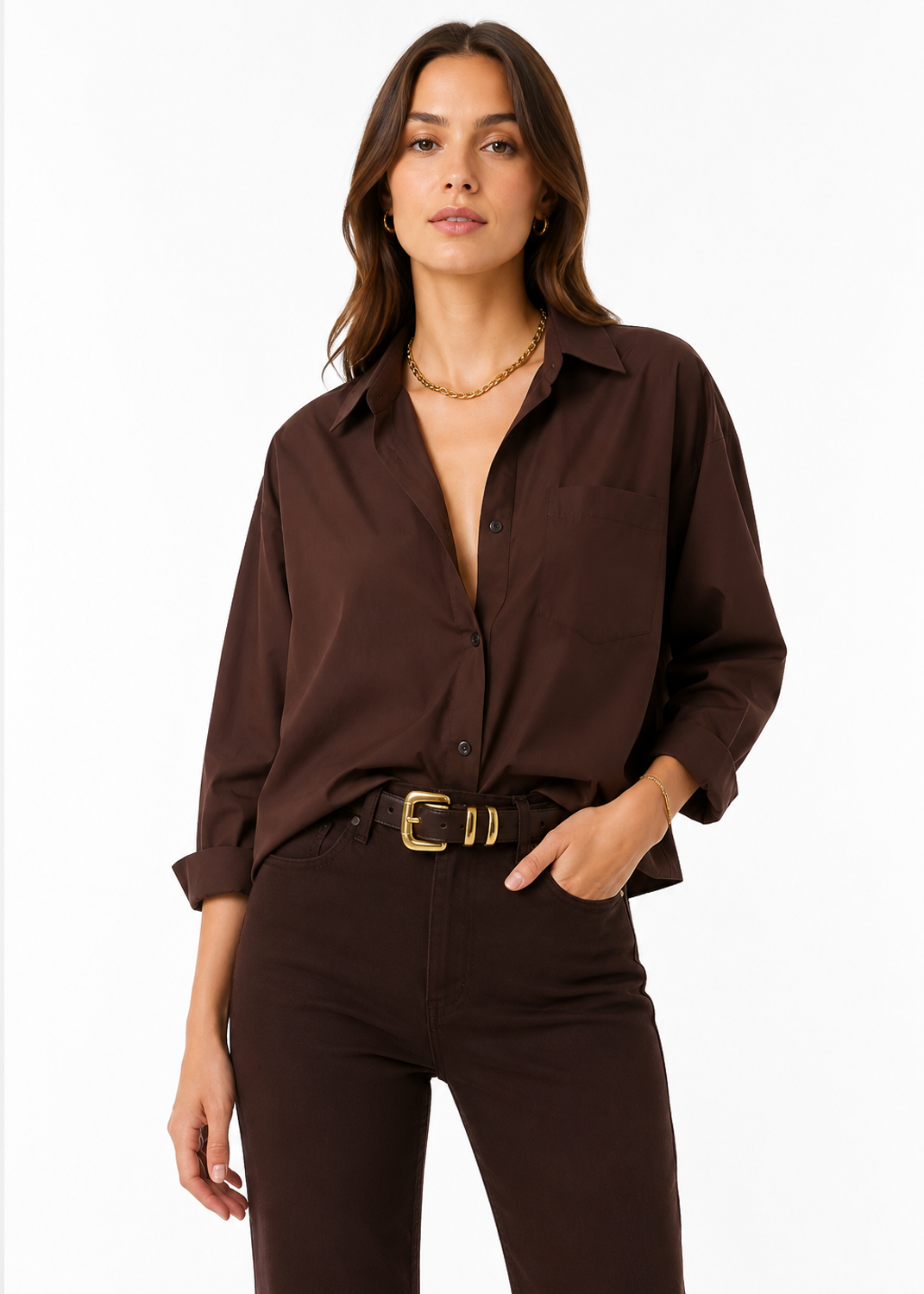 A woman modeling a dark brown button-down shirt with rolled sleeves and a chest pocket, paired with dark brown pants and a gold belt, against a plain white studio background.
