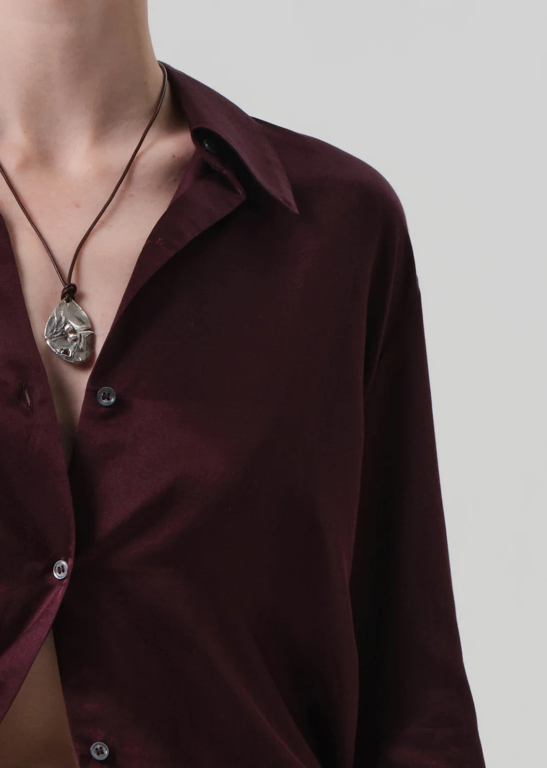 Camilia shirt burgundy displayed on model showing a close-up of the fabric and unique necklace.