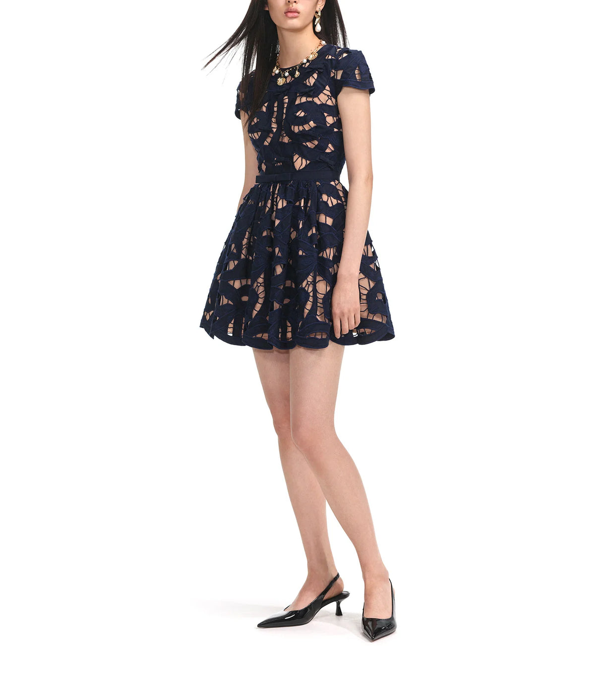 Three-quarter view of the navy bow embroidered mini dress worn with black slingback heels