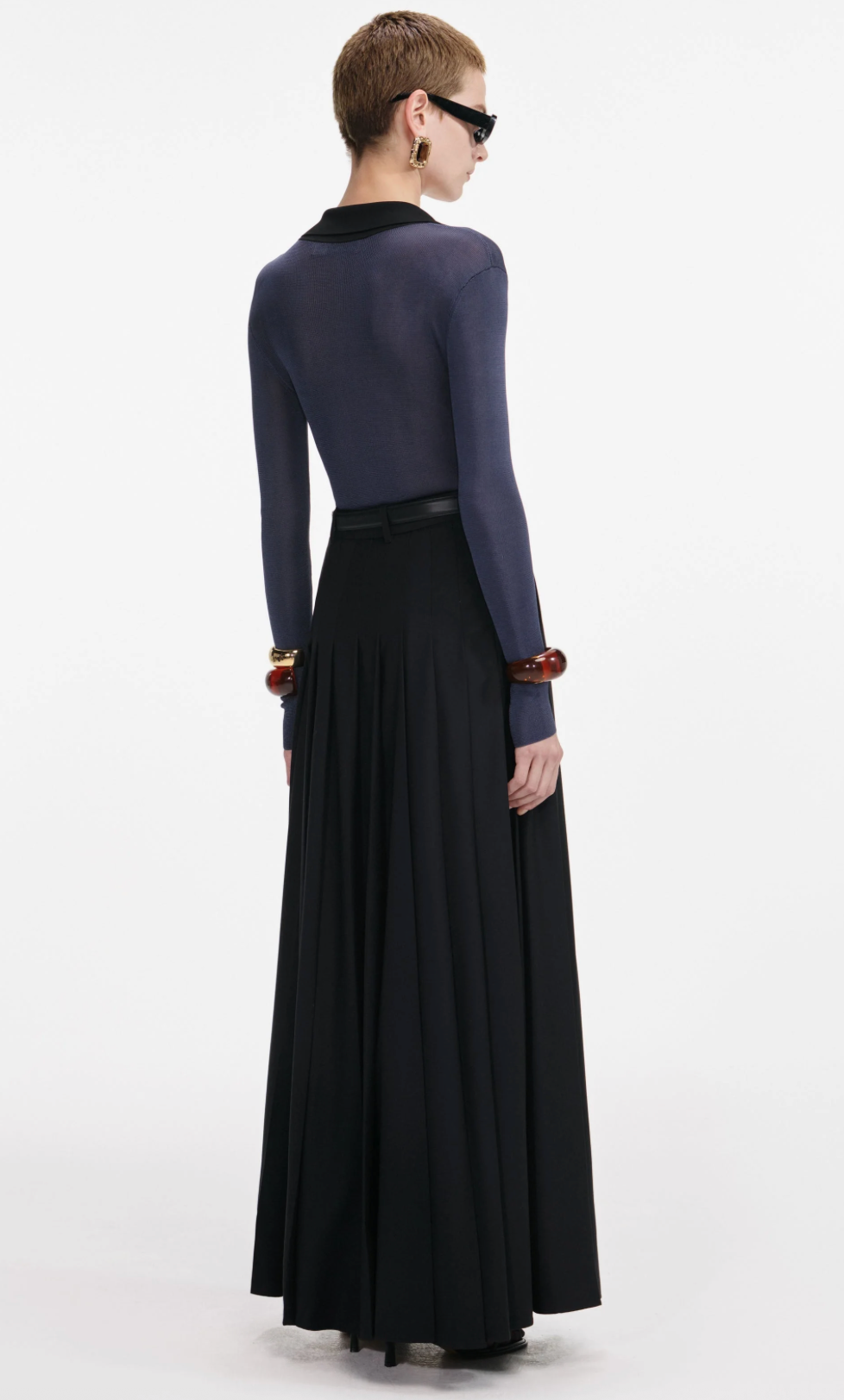 Person wearing a long-sleeve top and black skirt on a white background