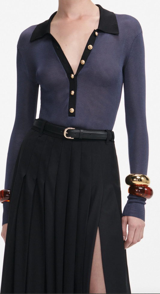 Woman wearing a navy long-sleeve top with black collar and skirt on a white background
