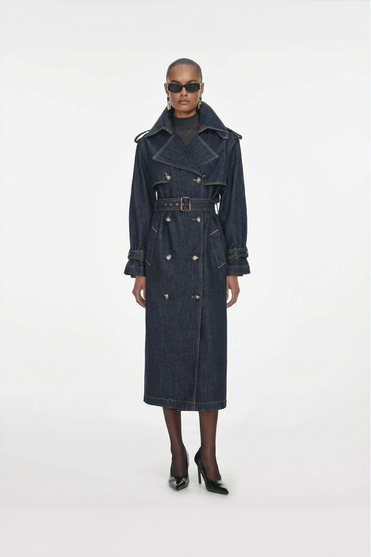 A model wearing a long dark blue denim coat on a white background